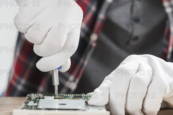 Technician repairing computer motherboard with screwdriver