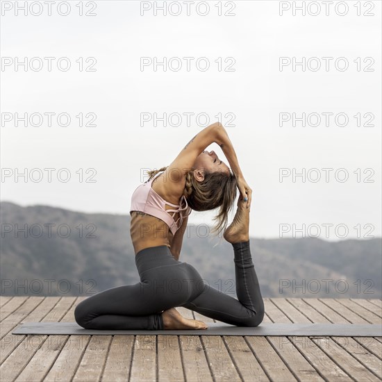 Side view woman doing yoga outdoors