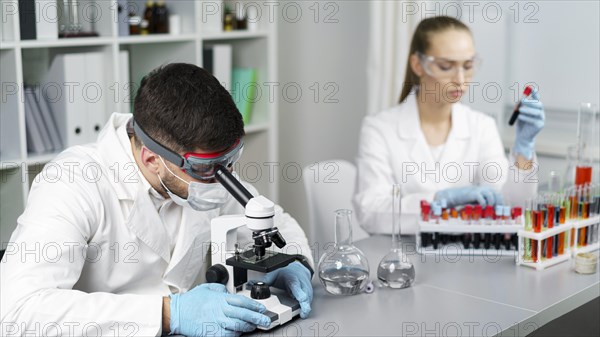 Female researcher male colleague laboratory with test tubes safety glasses