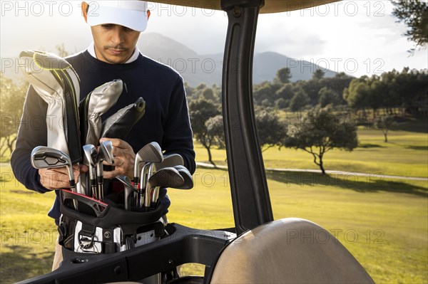 Front view man putting clubs golf cart