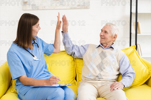 Medium shot caregiver high fiving with old man