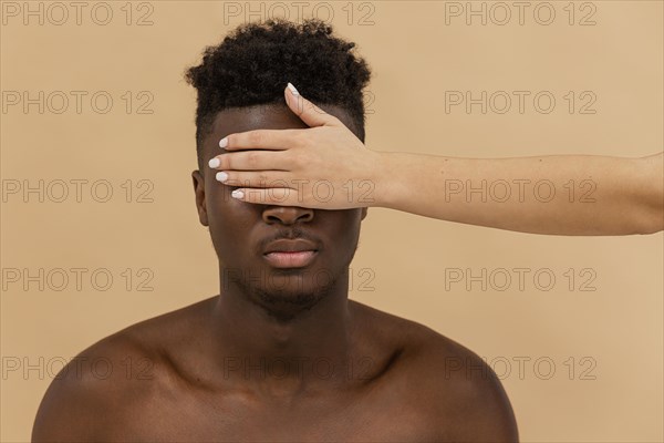 Close up white hand covering black man eyes