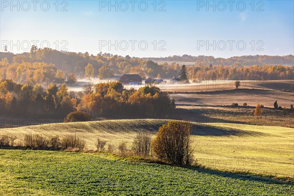 Landscape view on a foggy autumn morning with a red barn