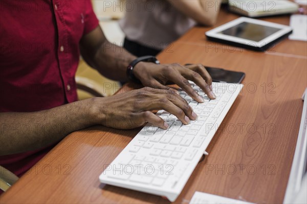Crop black man typing keyboard