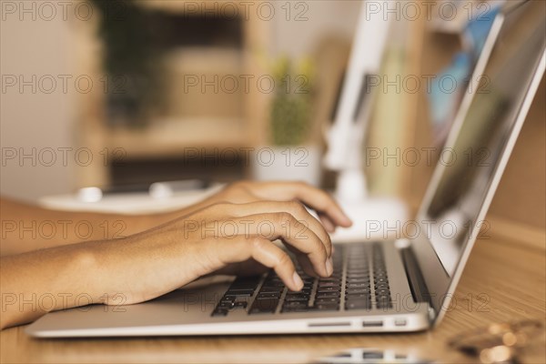 Hands typing laptop lateral view