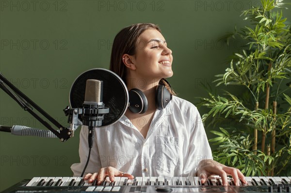 Front view smiley female musician playing piano keyboard indoors