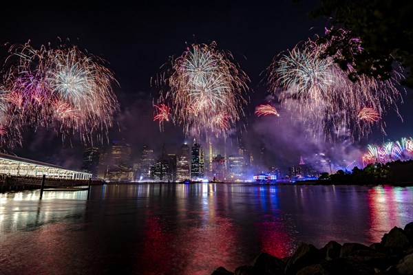 Independence day celebration in New York City with Macy's Fireworks in Lower Manhattan on East River and Brooklyn Bridge