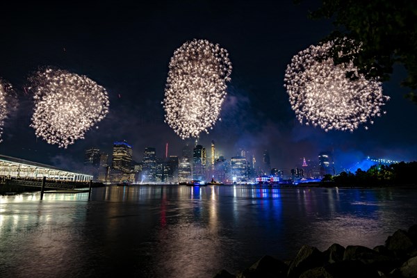 Independence day celebration in New York City with Macy's Fireworks in Lower Manhattan on East River and Brooklyn Bridge