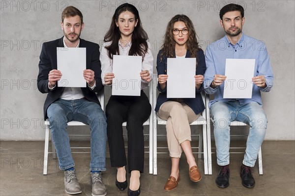 Front view people waiting their job interviews holding blank papers