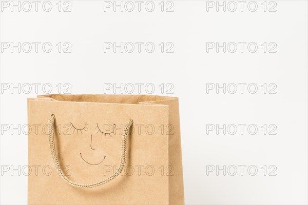 Human face drawn brown paper bag against white surface