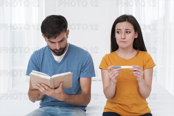 Worried woman holding pregnancy test with man reading