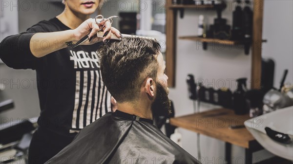 Woman combing haircutting man