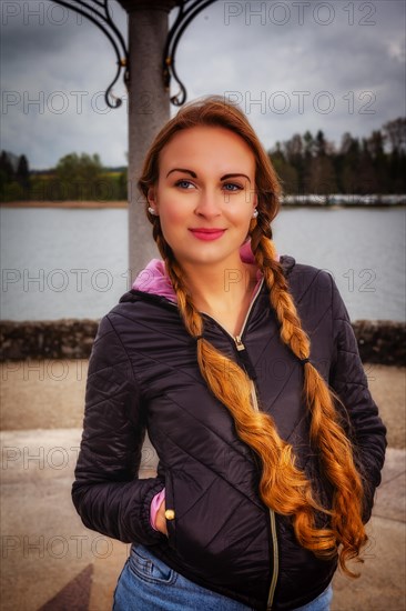 Portrait of a young woman with long braids dressed in an anorak in rainy weather