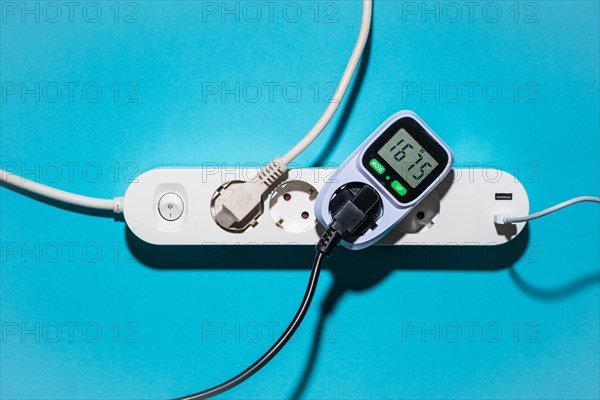 Top view of an energy cost meter in a power strip against a blue background