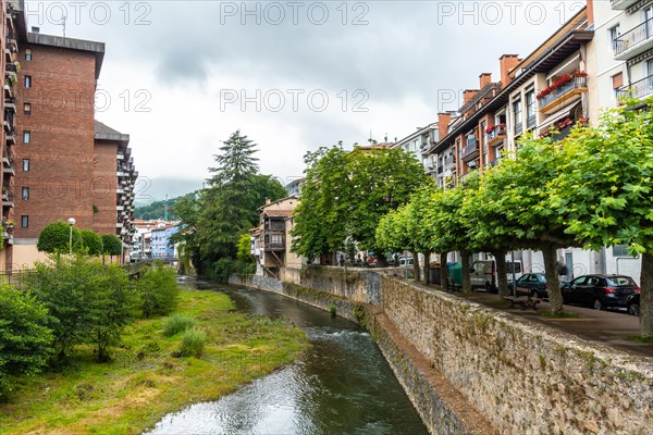 Traditional houses in the town of Azkoitia next to the Urola river and Church of Santa Maria La Real in the background