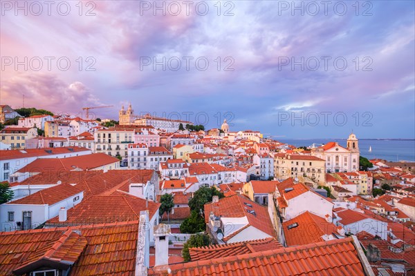 View of Lisbon famous view from Miradouro de Santa Luzia tourist viewpoint over Alfama old city district on sunset with dramatic overcast sky. Lisbon