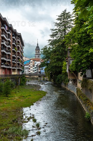 Traditional houses in the town of Azkoitia next to the Urola river and Church of Santa Maria La Real in the background