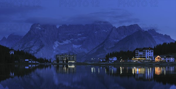 The mountain range Gruppo del Sorapis and hotels at night along lake Lago di Misurina in Auronzo di Cadore