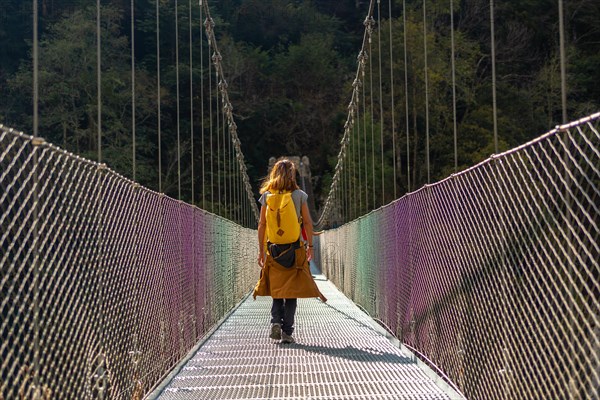 A hiker with a yellow backpack crossing the Holtzarte suspension bridge