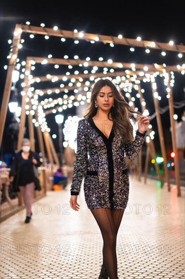 Winter lifestyle at Christmas. Brunette Caucasian girl in a fashionable sequined dress and black high heels