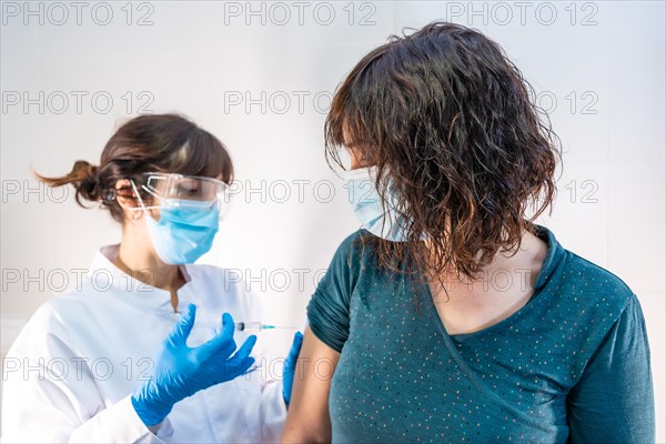 A female doctor with a face mask applying the coronavirus vaccine