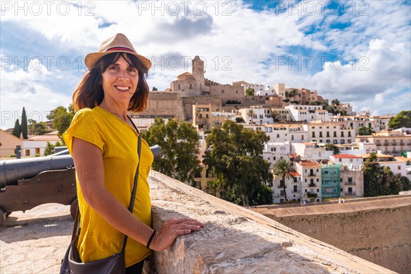 A young woman on vacation looking at the cathedral of Santa Maria de la Neu from the castle wall of Ibiza