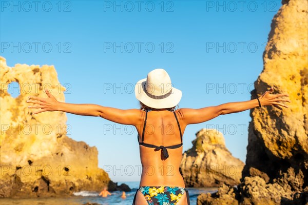 A woman with a hat on vacation at Praia dos Arrifes