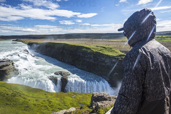 A young man above the Gullfoss waterfall in the golden circle of the south of Iceland