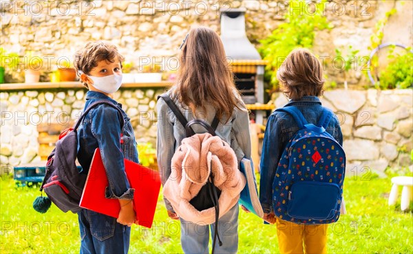 Three brother children with face masks ready for going back to school. New normality