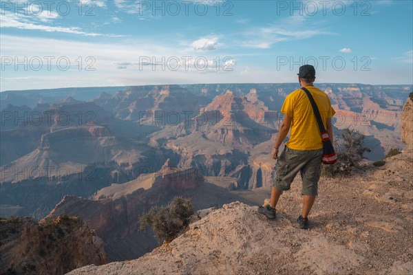 A man in a yellow shirt enjoying the sunset views at Mojave Point in Grand Canyon. Arizona