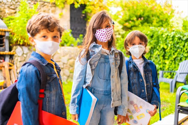 Three brother children with face masks ready for going back to school. New normality