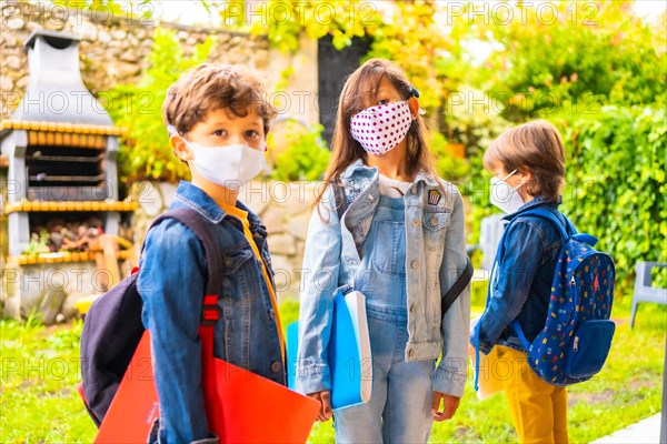 Three brother children with face masks ready for going back to school. New normality