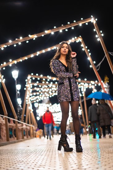 Winter lifestyle at Christmas. Brunette Caucasian girl in a fashionable dress with sequins and black high heels