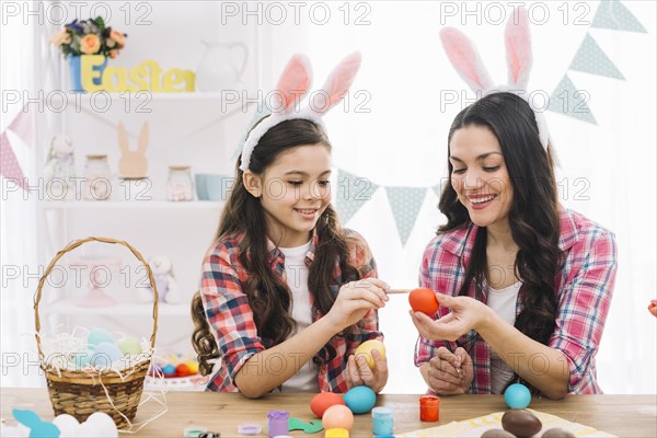Close up girl mother coloring eggs easter home