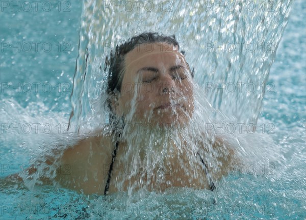 Woman Face with Eyes Closed Enjoying in a Waterfall in a SPA Pool in Switzerland