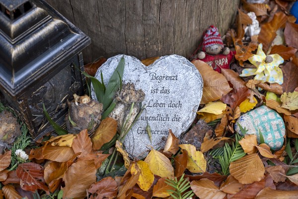 Mementos and stones in the shape of a heart on a memorial tree with the names of the buried