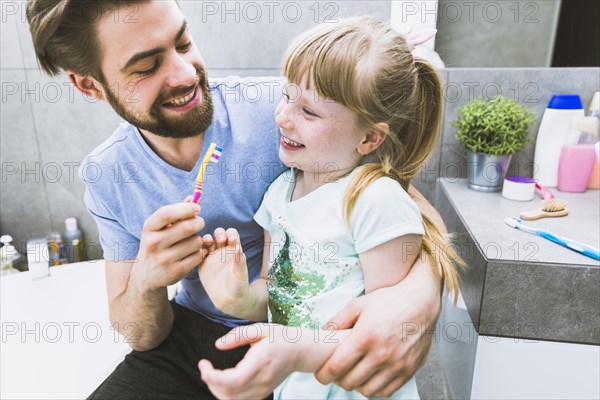 Cheerful father daughter brushing teeth