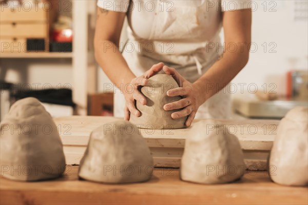 Midsection female craftswoman giving shape clay wooden table