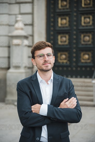Portrait confident young businessman with his arms crossed
