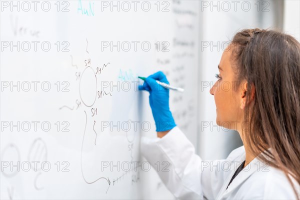 Close-up photo of a scientist conducting a study and using white board to write data with a scholarship in a laboratory