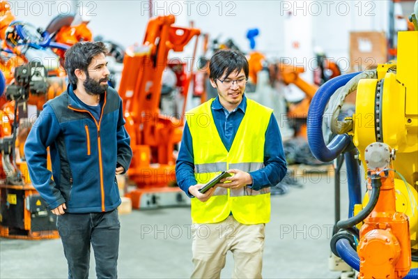 Team of engineers inspecting the machine in a robotic arm production line