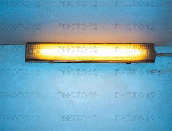 Yellow neon light over blue wall with copy space