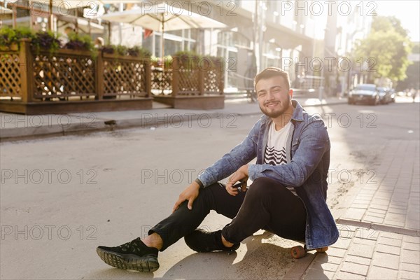 Portrait young male skateboarder looking camera