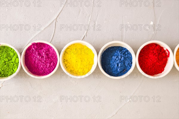 Row holi color powder bowls concrete textured background