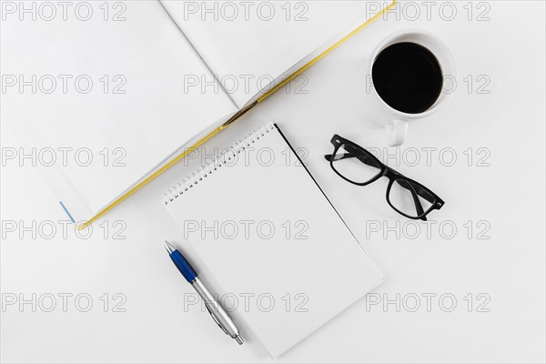 Spiral notepad spectacles cup pen book white background
