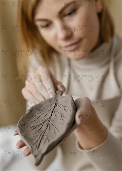 Close up blurry woman holding clay leaf