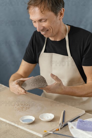 Close up smiley man doing pottery