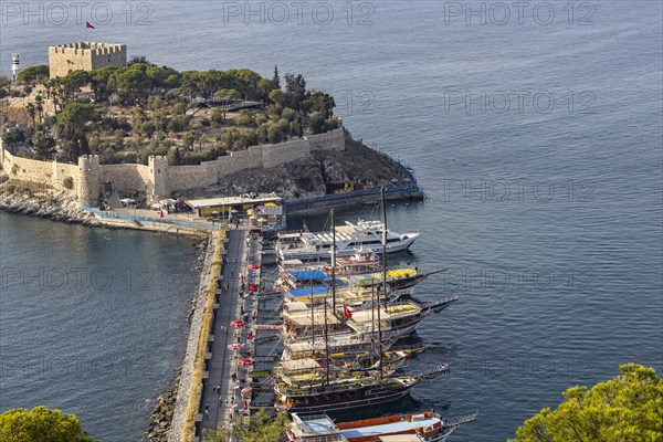 Excursion boats moored at the causeway to Pigeon Island in the bay of Kusadasi. A Genoese fortress towers on the summit of the island Kusadasi