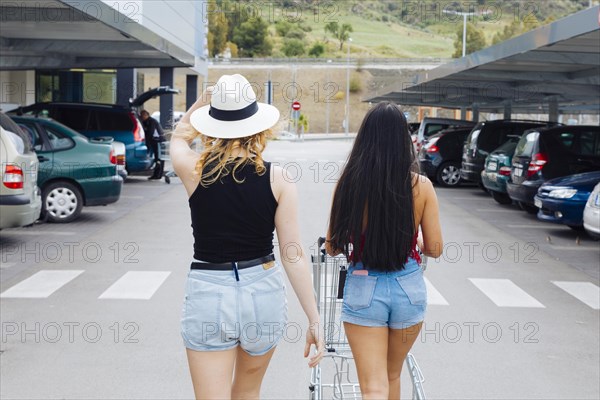 Women walking car with products shopping trolley from supermarket