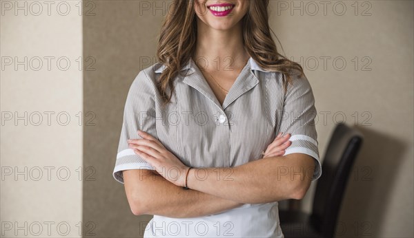 Close up smiling chambermaid standing with her arms crossed